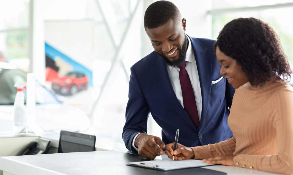 A Black African professional signing a new purchase agreement at the dealership